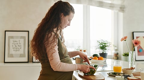 A pregnant woman making a salad.