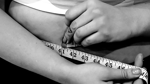 A woman measuring her waist with a measuring tape.