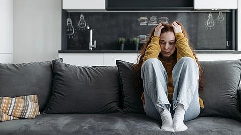 A young woman sitting on a sofa ,  feeling distressed and emotional