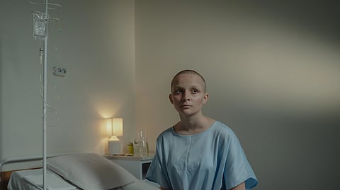child with cancer sitting on the bed