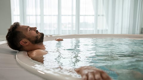 A serene moment of relaxation as a man enjoys a dip in an indoor pool, emphasizing self-care and tranquility