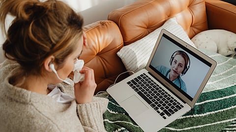 Woman having an online medical consultation on a laptop from her cozy sofa