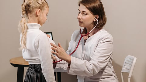 woman doctor examining a child patient using a stethoscope 
