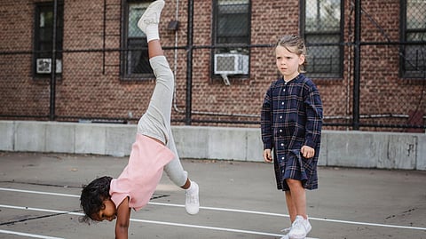 A girl doing a cartwheel and another girl standing next to her.