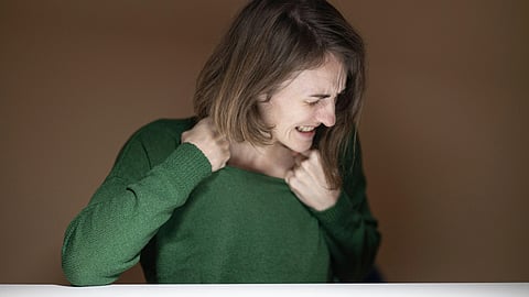 A girl in green sweater itching her neck.