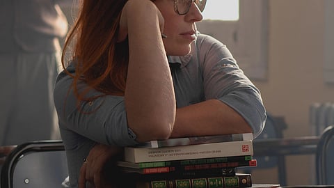 women daydreaming with hands on the book stack