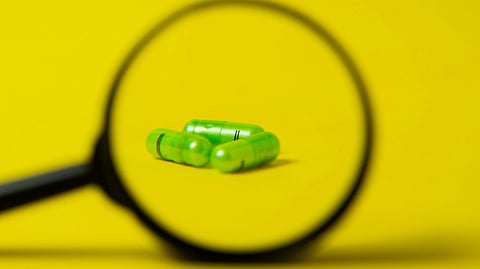 magnifying lens placed next to green pills
