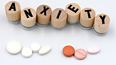 Image of anxiety pills and wooden blocks forming the word 'anxiety' on a white background