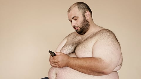 Plus-size bearded man sitting and using smartphone. Focus on lifestyle and technology in a relaxed setting