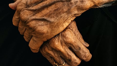 close up picture of an old person's hand wearing a gold ring
