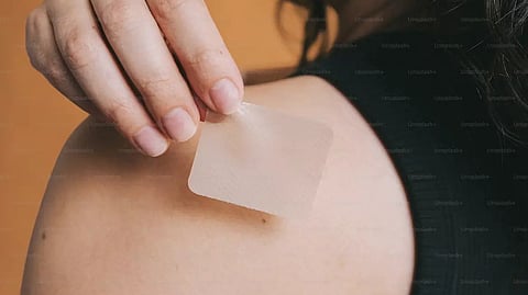 person applying a small square patch to their shoulder