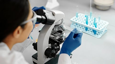 Doctor conducting research in a lab using a microscope and dropper