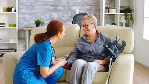 Female nurse talking with old woman at home