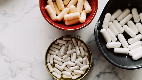 Top view of various capsules in bowls placed on a marble surface, emphasizing healthcare and medication themes