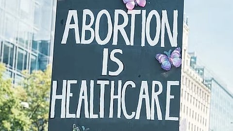 A protest sign reading "Abortion is Healthcare" with colorful butterfly decorations. 