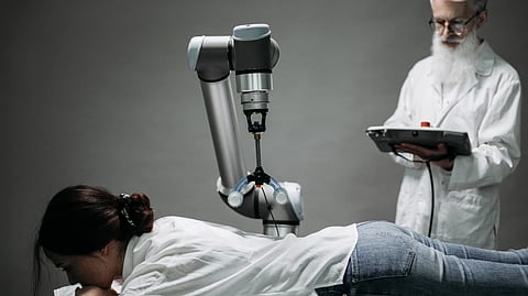 A woman receives a robotic massage as a scientist monitors, showcasing modern technology