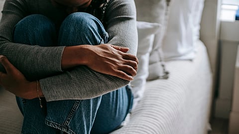 woman sitting on a bed hugging her legs