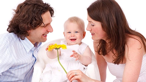 A joyful family moment with parents and baby holding a flower