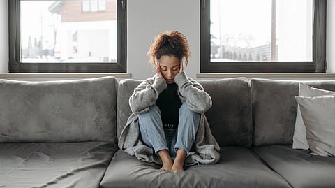 A girl sitting on couch in grey.