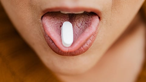 A white tablet on tongue.