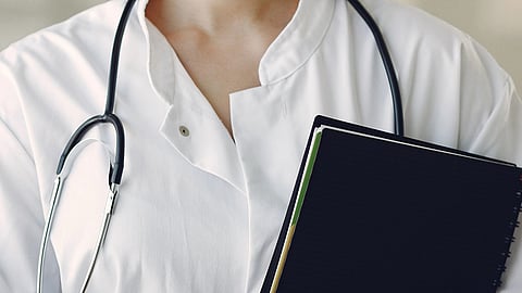 A doctor wearing white coat and stethoscope around neck.