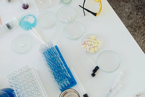 Aerial view of laboratory equipment including petri dishes, pills, test tubes, and syringes