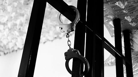Hand cuffs on prison bars.