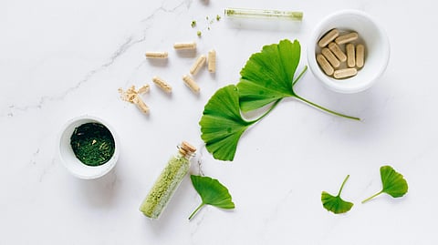 Flat lay of herbal supplements with ginkgo leaves on marble surface, emphasizing natural health remedies