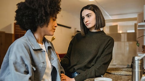 Two women sharing a comforting moment over coffee indoors, expressing unity
