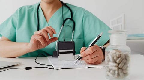 A medical professional writing a prescription in a clinical setting