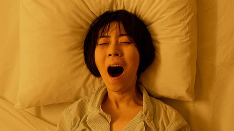 A woman yawning in bed.