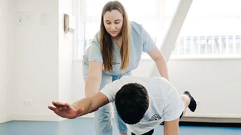A physiotherapist assists a patient in stretching exercises indoors