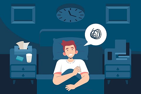 Man sitting on his bed at 4:40 a.m., unable to sleep during early addiction recovery.