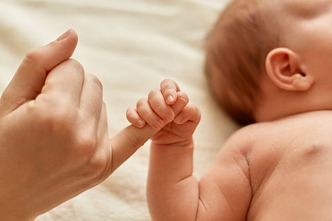 infant holding mommy's finger
