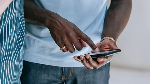 A person holding a phone and pointing towards the screen.
