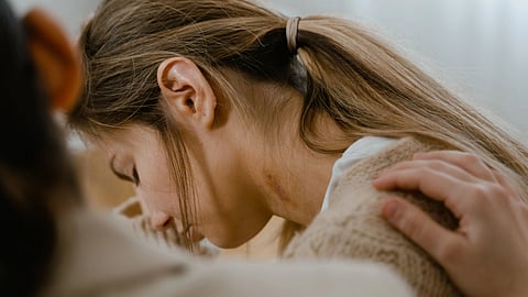woman crying with a hand on her shoulder
