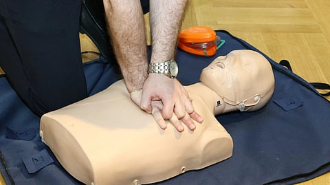 Hands performing CPR on a training dummy using realistic techniques indoors