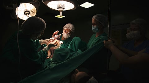 Doctors and nurses delivering a newborn baby under surgical lights in a hospital