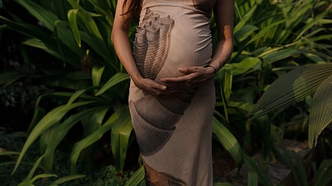 pregnant women holding belly in garden