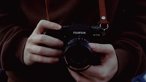 Close-up shot of hands holding a Fujifilm camera