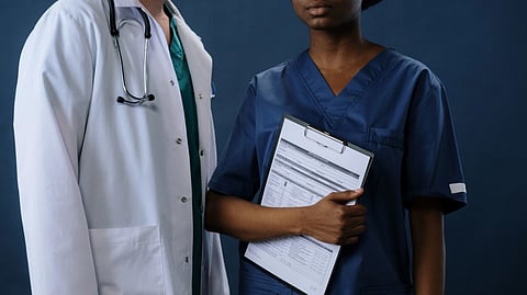 Two healthcare professionals in scrubs and lab coat with a clipboard