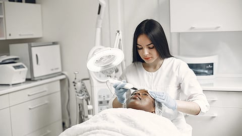 A woman performing skin treatment on a client’s face.