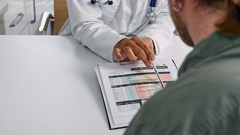 A doctor showing something to a patient through a chart on table.