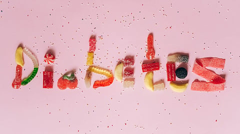 Candies shaped to spell diabetes on a pink background, highlighting sugar intake