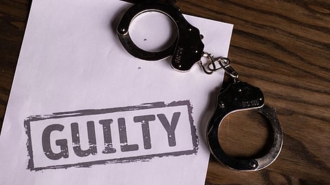Top view of handcuffs on paper with 'GUILTY' text, symbolizing a verdict or crime