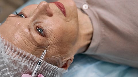 A senior woman undergoes a cosmetic injection procedure in a medical facility