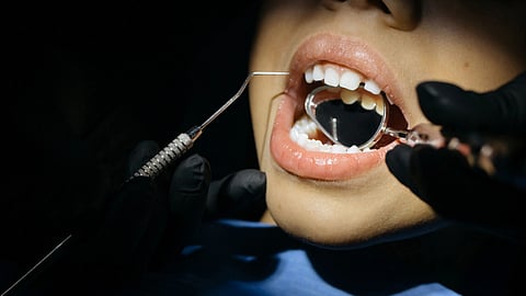 A close-up view of a child undergoing a dental examination with tools in their mouth