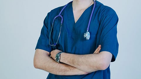 A doctor with a stethoscope around neck in blue uniform.