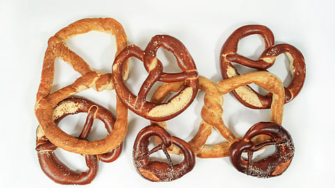 Top view of assorted fresh and salty pretzels on a white background, perfect for snack-themed photography