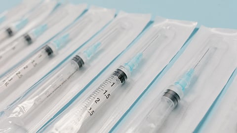 Close-up of sterile syringes aligned on a light blue surface
